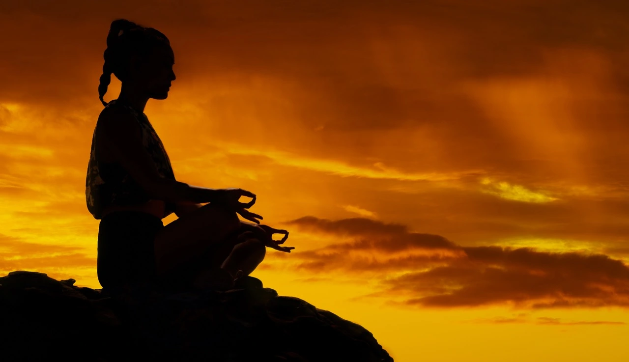 Kobieta medytuje na tle zachodu słońca